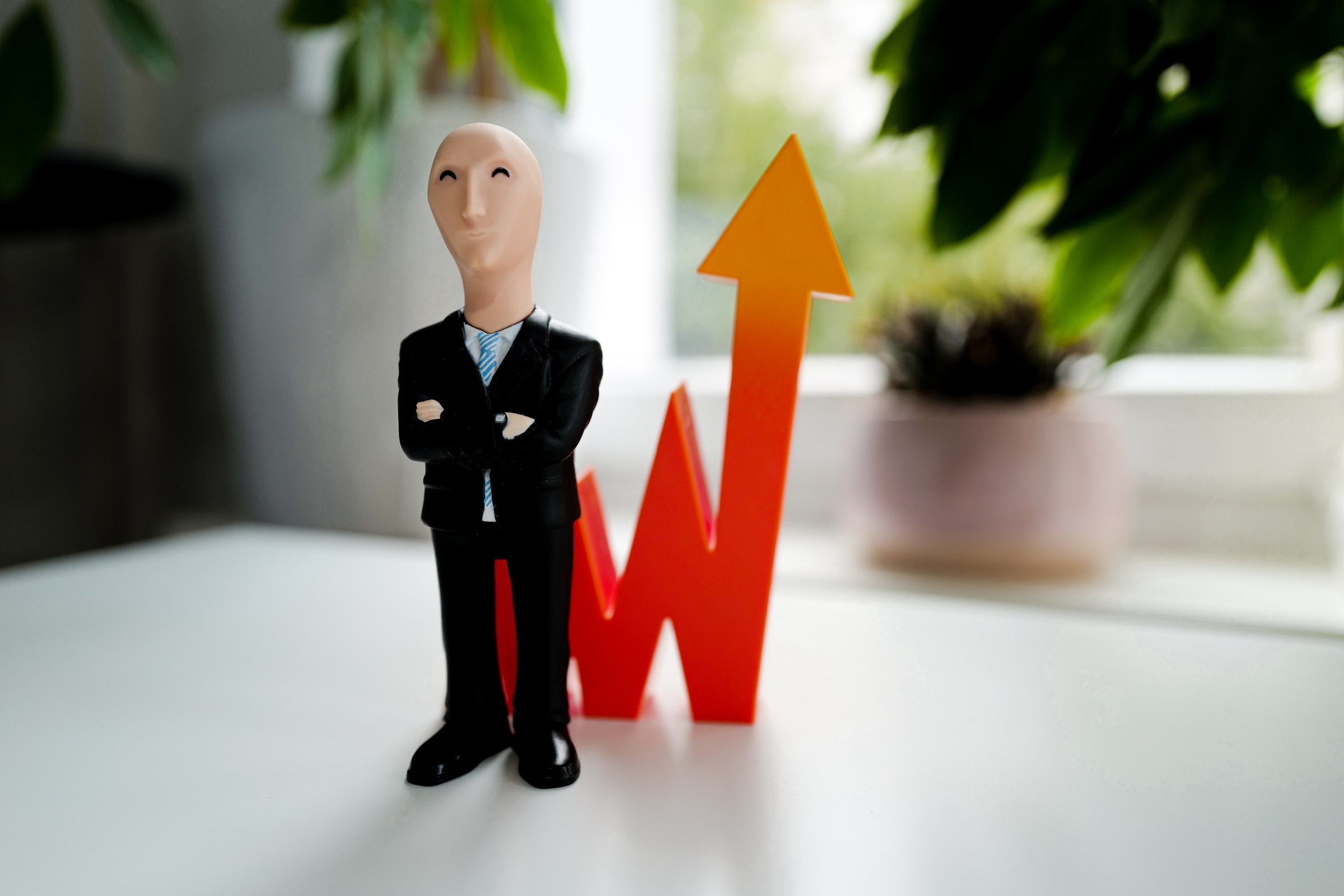 Une figurine « Stonks » à côté d'une courbe de graphique montant en flèche