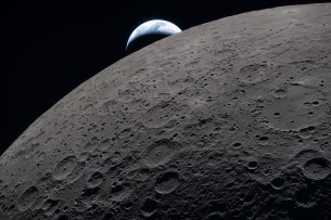 art002e009289 (April 6, 2026) – The lunar surface fills the frame in sharp detail, as seen during the Artemis II lunar flyby, while a distant Earth sets in the background. This image was captured at 6:41 p.m. EDT, on April 6, 2026, just three minutes before the Orion spacecraft and its crew went behind the Moon and lost contact with Earth for 40 minutes before emerging on the other side.
In this image, the dark portion of Earth is experiencing nighttime, while on its day side, swirling clouds are visible over the Australia and Oceania region. In the foreground, Ohm crater shows terraced edges and a relatively flat floor marked by central peaks — formed when the surface rebounded upward during the impact that created the crater.